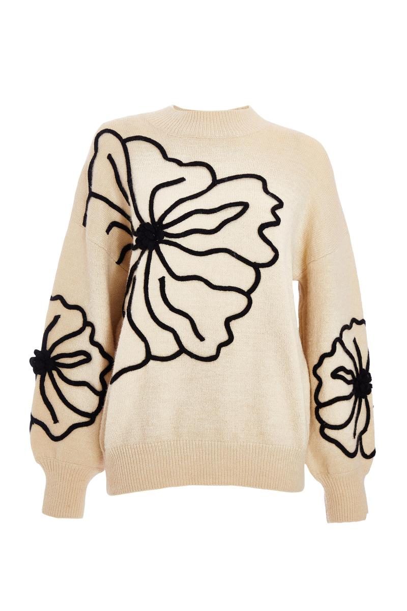 Біля білого в’язаного квіткового джемпера