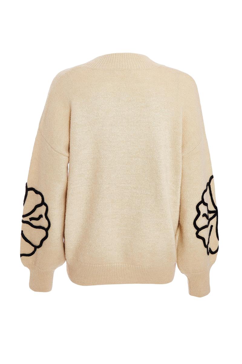 Біля білого в’язаного квіткового джемпера