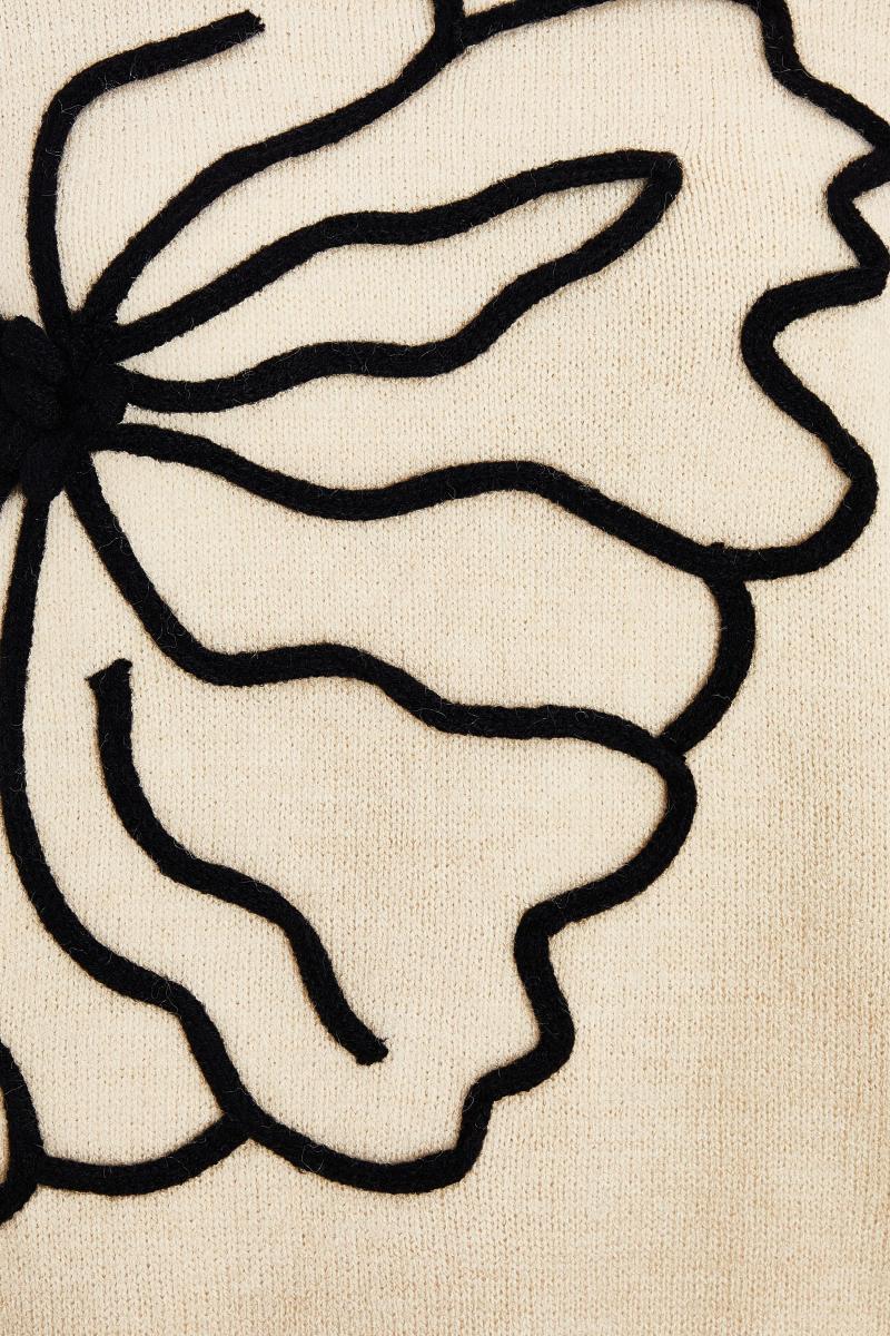 Біля білого в’язаного квіткового джемпера